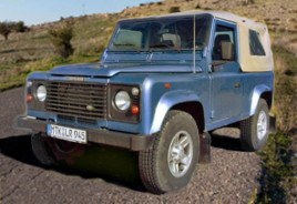 Blauer Land Rover Defender auf einer Gebirgsstraße