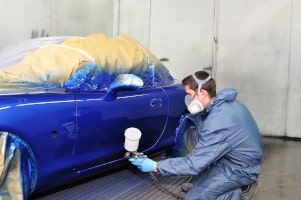 Fahrzeuglackierer beim Lackierne des Autos