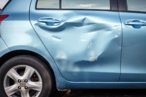 Nahaufnahme einer Autotür nach einem Unfall, die auszubeulen und zu lackieren ist.