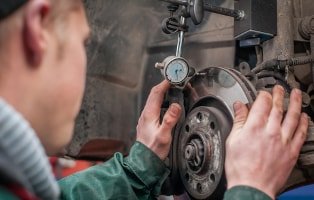 Fachmann beim Wechseln der Bremsen bei einem Fiat in der Werkstatt