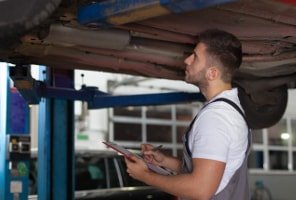 Fachmann untersucht den Unterboden des Autos beim Frühjahrscheck