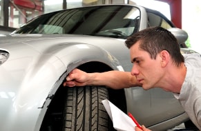 Kfz Sachverständiger beim Schadensgutachten eines silberen Autos