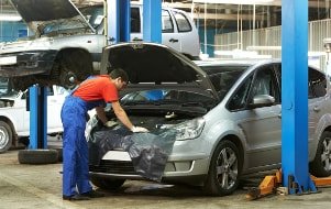 Fachmann wechselt das Servoöl nach dem Prüfen des Servolenkungssystems in einer Werkstatt