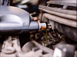 Un spécialiste change l'huile moteur d'une voiture.